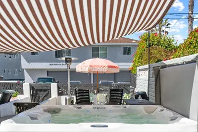 a hot tub with an umbrella on a patio at Day in Paradise at Oside Palms in Oceanside