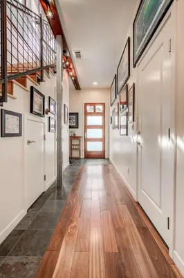 a hallway with white walls and wood floors and a staircase at The Craftsman Coastal Cottage in Leucadia in Encinitas