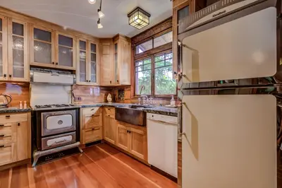 a kitchen with wooden cabinets and a refrigerator at The Craftsman Coastal Cottage in Leucadia in Encinitas