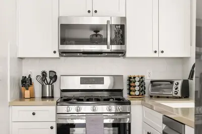 a kitchen with a stove and a microwave at Modern and Cozy in PB with Patio and Firepit in San Diego
