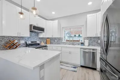 a white kitchen with white cabinets and a refrigerator at Ocean View Gem with Rooftop Deck and Hot Tub in San Diego