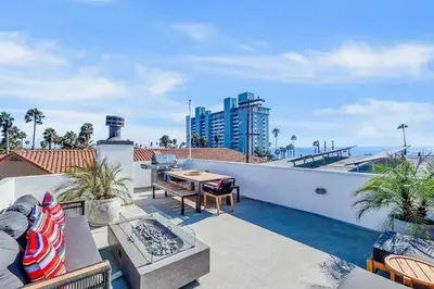 a patio with a table and chairs on a roof at Ocean View Gem with Rooftop Deck and Hot Tub in San Diego