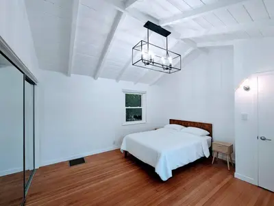 a white bedroom with a bed and a chandelier at La Jolla Retreat in San Diego