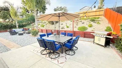 a table with chairs and an umbrella in a backyard at Oceanside Oasis - King Bed, Pet Friendly, Fire Pit in Oceanside