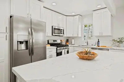 a kitchen with white cabinets and a stainless steel refrigerator at Luxury on Lewis By Cardo - Jacuzzi Fire Pit in San Diego