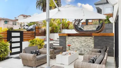 a patio with an umbrella and chairs and a hammock at Steps to BeachShops Oceanview Hot TubFirepit Moonlight Modern by AvantStay in Encinitas
