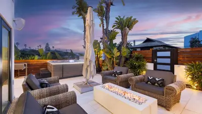 a patio with couches and a fireplace on a balcony at Steps to BeachShops Oceanview Hot TubFirepit Moonlight Modern by AvantStay in Encinitas