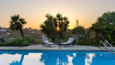 a swimming pool with two chairs and palm trees at Rancho Real by AvantStay Private Pool Hot Tub Luxe Group Retreat in Rancho Santa Fe