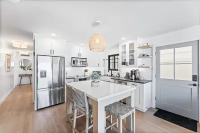 a white kitchen with a white table and chairs at Luxury Ground S Oceanfront Unit with Boardwalk Lounge Firepit - AC in San Diego