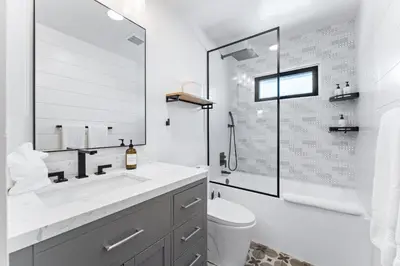a white bathroom with a toilet and a sink at Luxury oceanfront fourplex with roof deck sleeps 22 in San Diego