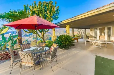 a patio with a table and chairs and a red umbrella at Gorgeous Private Estate with Pool & Pickleball Court in Lakeside