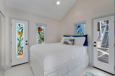 a white bedroom with a bed and stained glass windows at The Shining Sea A in Oceanside