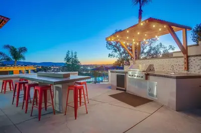 a outdoor kitchen with a bar with stools at Large Pool Home on Two Acres with Views! in Vista