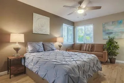 a bedroom with a bed and a couch and a ceiling fan at Large Pool Home on Two Acres with Views! in Vista