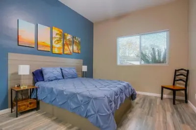 a bedroom with a bed with blue sheets and a window at Large Pool Home on Two Acres with Views! in Vista