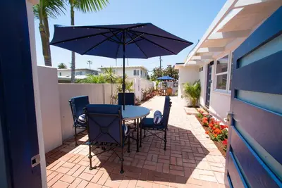 a table and chairs with an umbrella on a patio at La Jolla Windansea Luxury Apt in San Diego