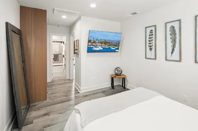 a white bedroom with a bed and a tv at Modern 1 BR Apt - Walk to Ocean & Cafes in San Diego