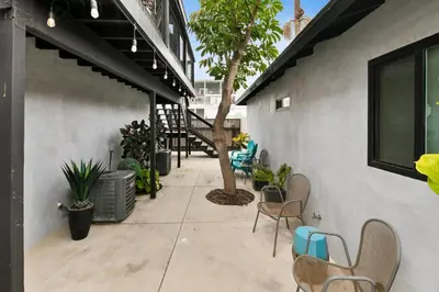 a patio with chairs and a tree next to a building at Modern 1 BR Apt - Walk to Ocean & Cafes in San Diego