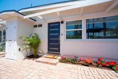a house with a blue door and some flowers at La Jolla Windansea Luxury Cottage in San Diego
