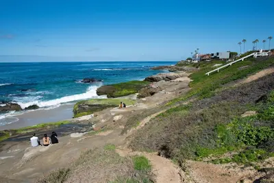 a group of people standing on a beach near the ocean at La Jolla Windansea Luxury Cottage in San Diego
