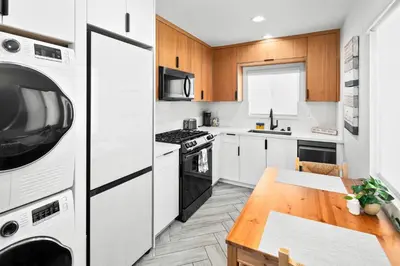 a kitchen with white cabinets and a wooden table at Modern 1 BR Beach Waves and Sunshine in San Diego