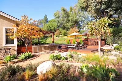 a backyard with a patio and a deck with chairs and an umbrella at The Sanctuary in Laguna Hills