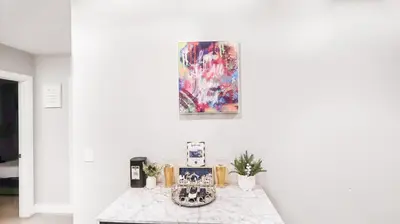 a table in a white room with a painting on the wall at Exotic Homes Gillespie Dr by SD stay in Spring Valley