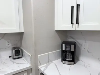 a kitchen with white cabinets and a coffee maker on the counter at Exotic Homes Gillespie Dr by SD stay in Spring Valley
