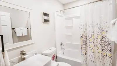 a white bathroom with a shower curtain and a toilet at Exotic Homes Gillespie Dr by SD stay in Spring Valley