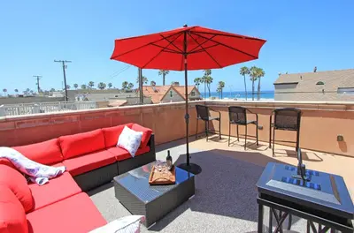 a red couch and an umbrella on a roof at Lower West Newport in Newport Beach