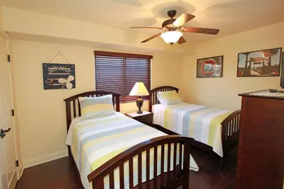 two beds in a room with a ceiling fan at Lower West Newport in Newport Beach