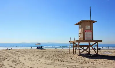 a lifeguard tower on a beach with people on the beach at Lower West Newport in Newport Beach