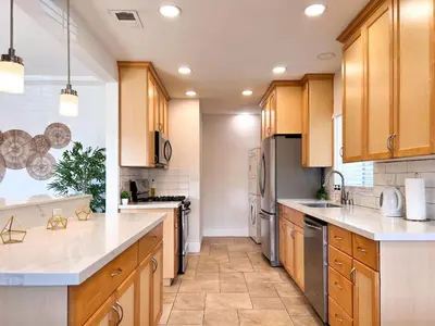 a large kitchen with wooden cabinets and white counter tops at Modern Boho Oasis - Fast Wifi & Shuffleboard! in San Diego