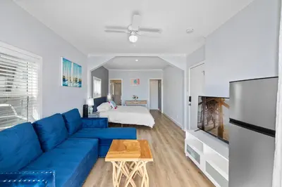 a living room with a blue couch and a bed at 1628 West Oceanfront Oasis - All Units in Newport Beach