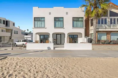 a white house with a palm tree on the beach at 1628 West Oceanfront Oasis - 5,8,9 in Newport Beach