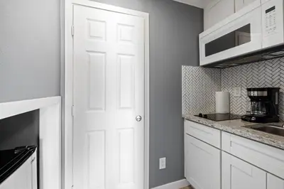 a kitchen with white cabinets and a white door at 1628 West Oceanfront Oasis 2 in Newport Beach
