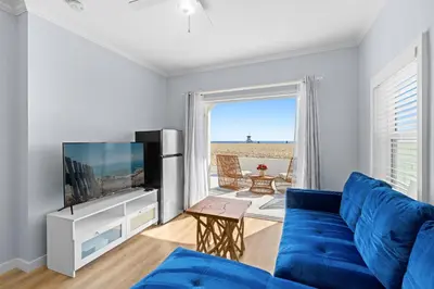 a living room with a blue couch and a flat screen tv at 1628 West Oceanfront Oasis 1,2,3 in Newport Beach