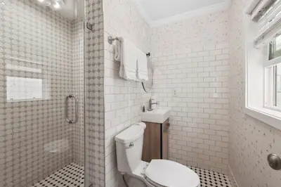 a white tiled bathroom with a toilet and a shower at 1628 West Oceanfront Oasis - 4,6,7 in Newport Beach