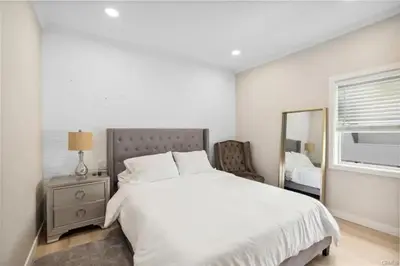 a white bedroom with a large bed and a mirror at 1628 West Oceanfront Oasis 9 in Newport Beach