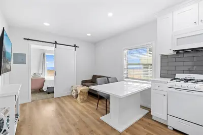 a white kitchen with a table and a couch at 1628 West Oceanfront Oasis 8 in Newport Beach