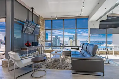 a living room with a blue couch and a large window at Cityscape Elegance with Water Views in San Diego