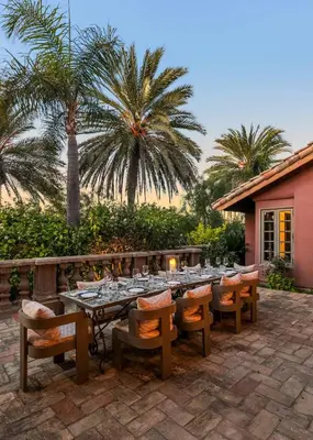 a dining table and chairs on a patio with palm trees at Exclusive Spanish Mediterranean Mansion in Rancho Santa Fe