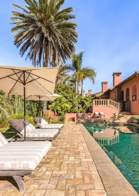 a pool with two lounge chairs and an umbrella at Exclusive Spanish Mediterranean Mansion in Rancho Santa Fe
