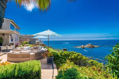 a patio with couches and an umbrella and the ocean at Dolphin's Paradise in San Diego