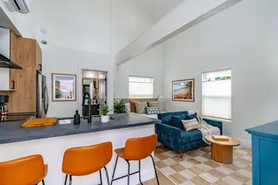 a kitchen and living room with a bar and orange chairs at Swanky Studio in Vibrant Hillcrest in San Diego