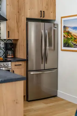 a stainless steel refrigerator in a kitchen with wooden cabinets at Swanky Studio in Vibrant Hillcrest in San Diego