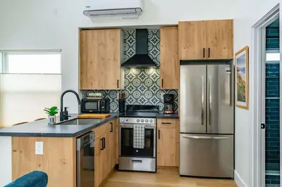 a kitchen with wooden cabinets and a stainless steel refrigerator at Swanky Studio in Vibrant Hillcrest in San Diego