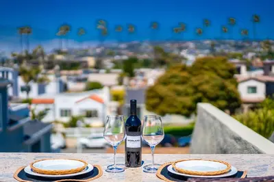 a table with two glasses and a bottle of wine at PB Compound Getaway Steps to Surf and Sand in San Diego