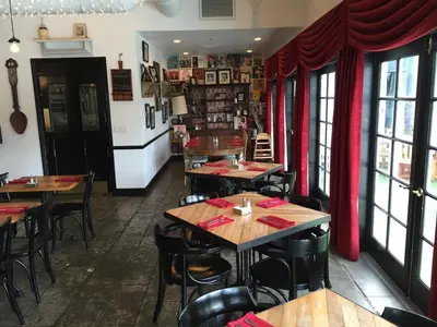 a restaurant with tables and chairs and red curtains at The Lafayette Hotel, Swim Club & Bungalows in San Diego