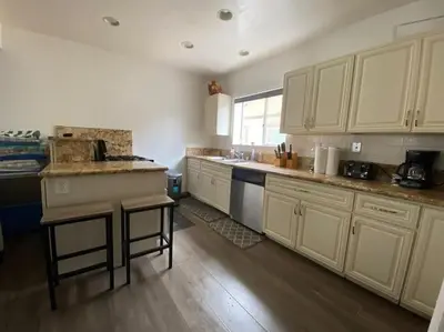 a kitchen with white cabinets and a wooden floor at Ocean View 5 BR with 3 decks and spa in San Diego